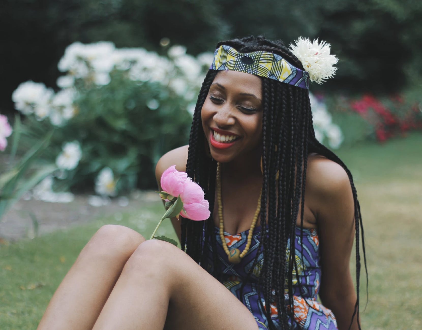 photography of a woman looking at flower