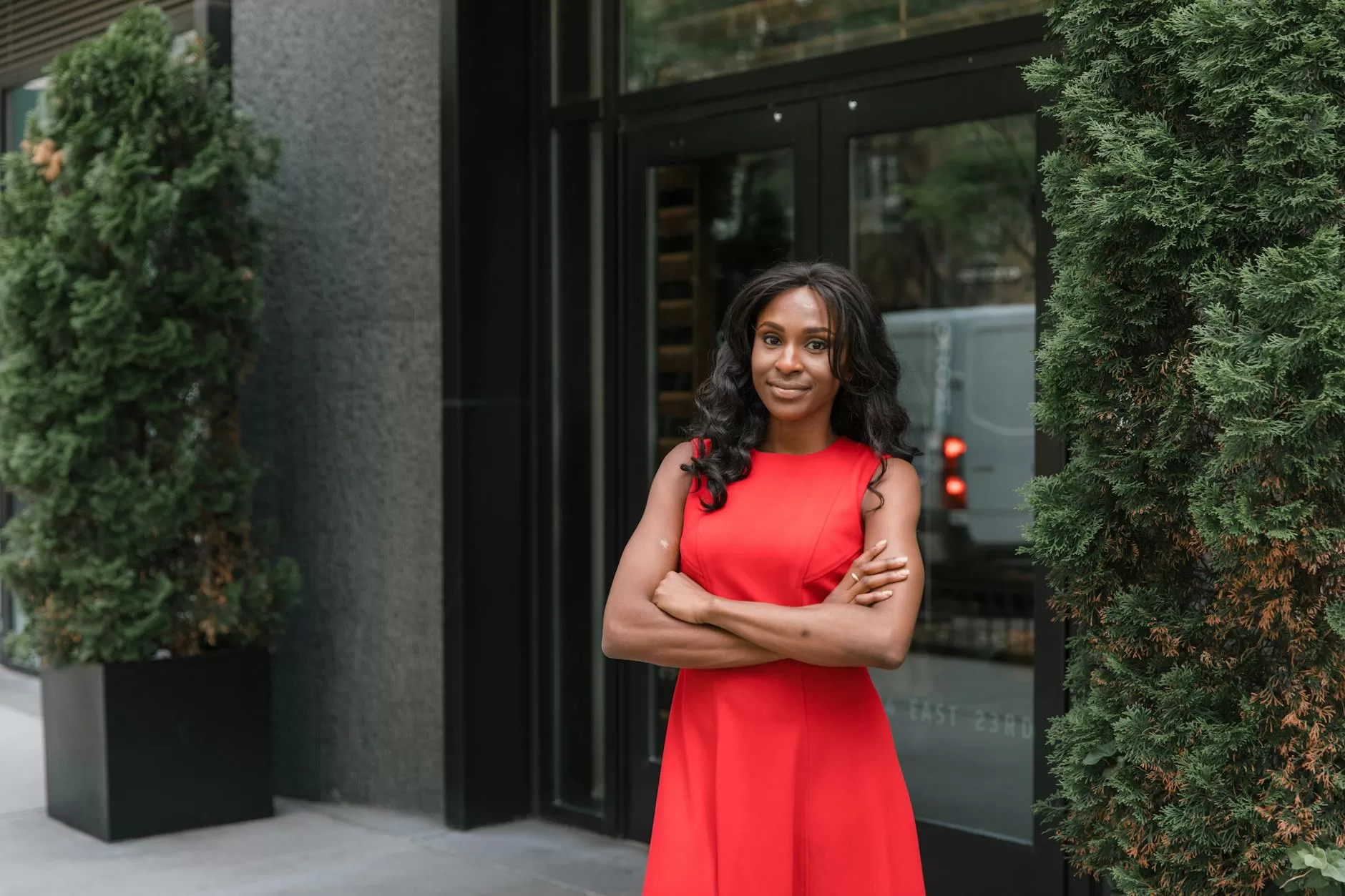 smiling woman in red dress in front of office building