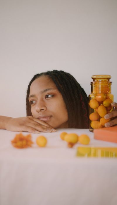 Black woman reading about blood type diets while planning healthy meals in a modern kitchen surrounded by fresh vegetables and wellness items.